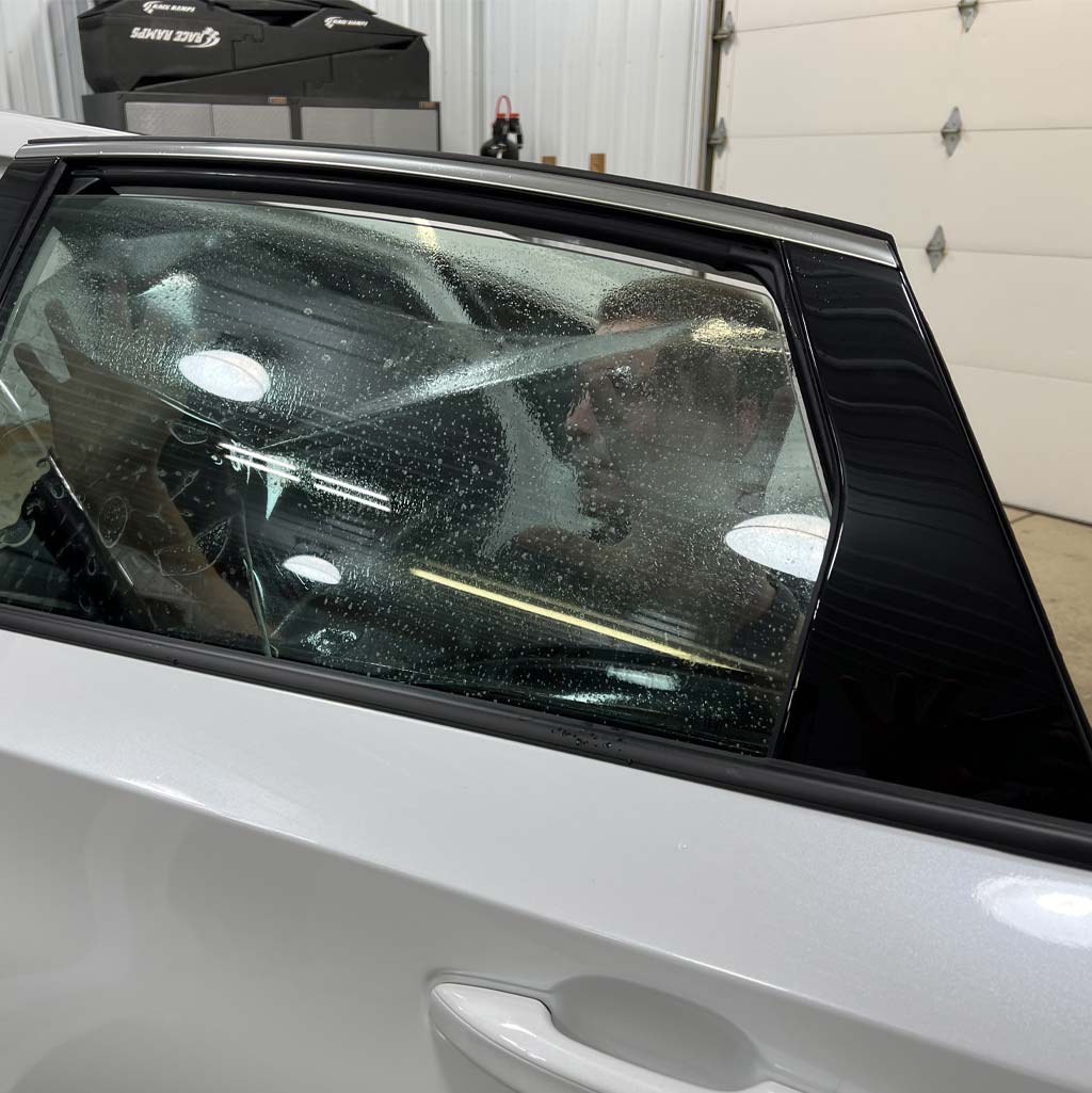 a man is sitting in the driver 's seat of a white car .