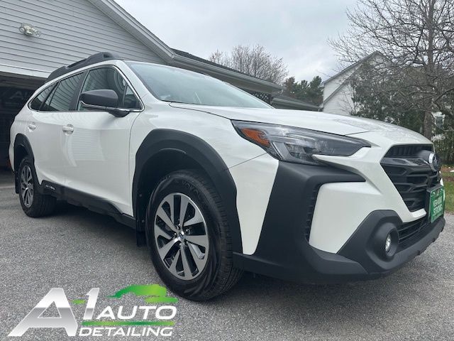 A white subaru outback is parked in front of a garage.