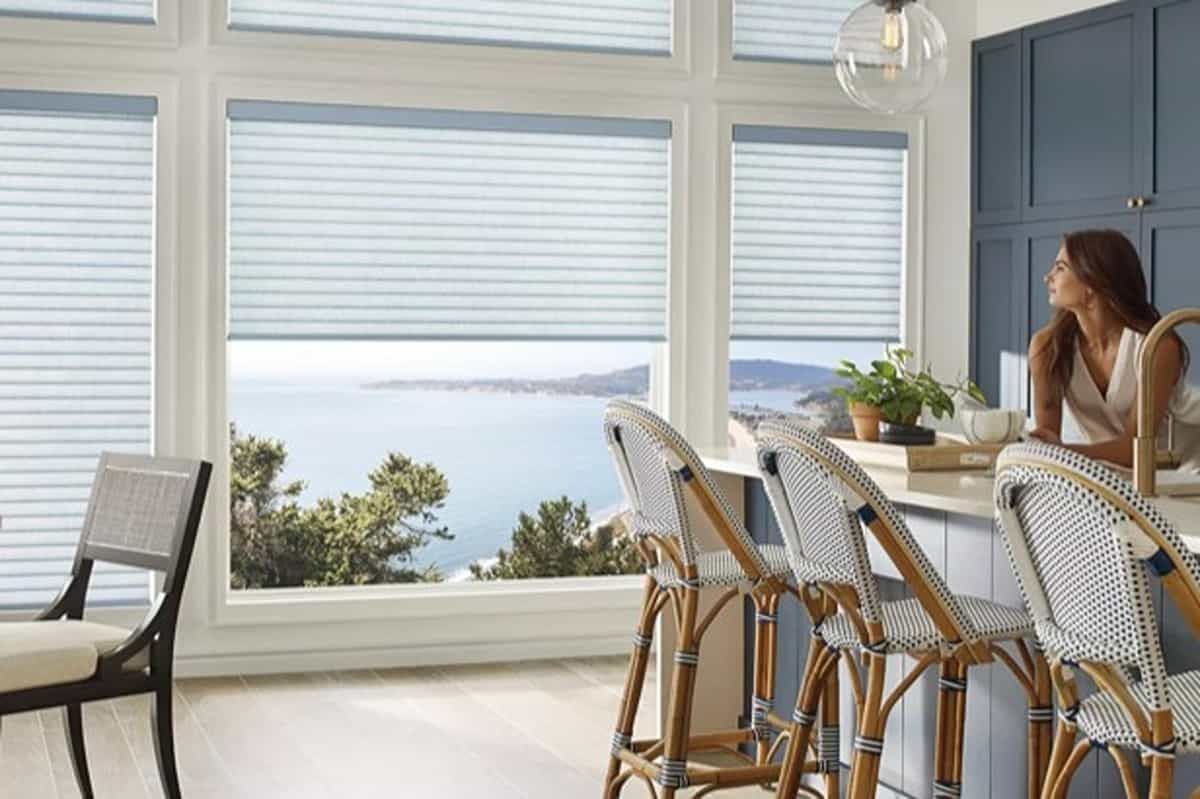 A dining area featuring Hunter Douglas Sonnette® Roller Shades with a view of water outside