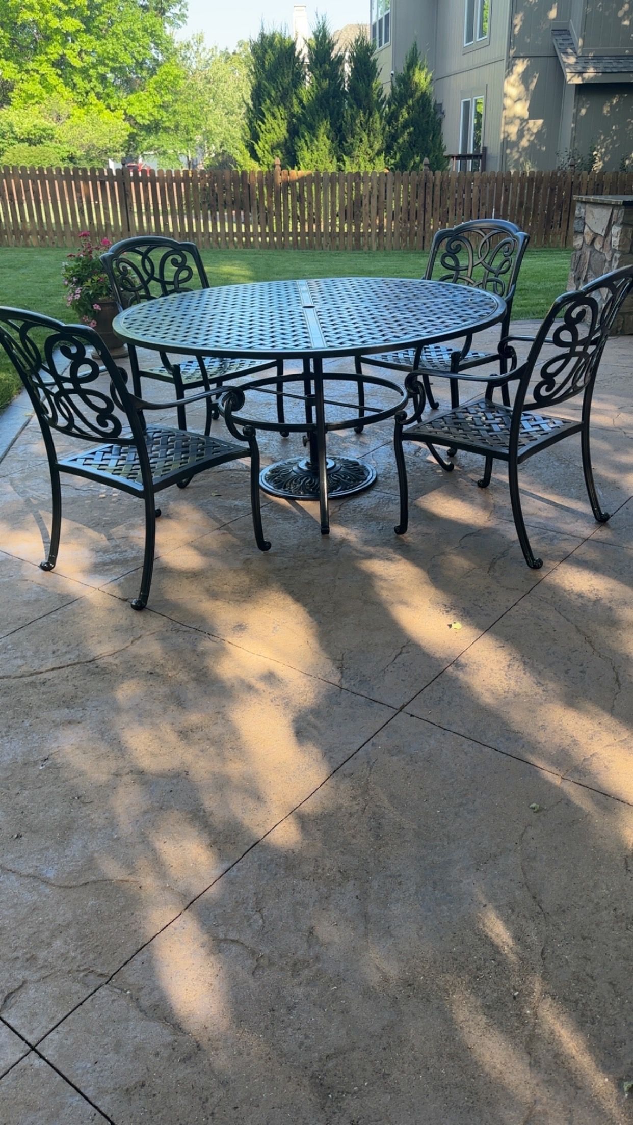Patio set with oval table and four ornate chairs on a patterned concrete patio.