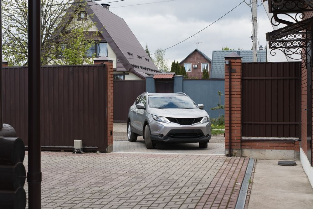 Gravel yard with a stone retaining wall, wooden fence, and a wheelbarrow next to a building.