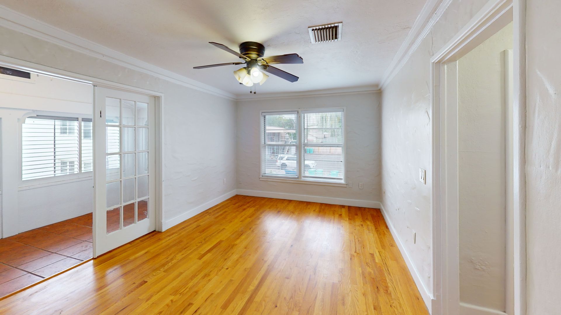 An empty living room with hardwood floors and a ceiling fan.