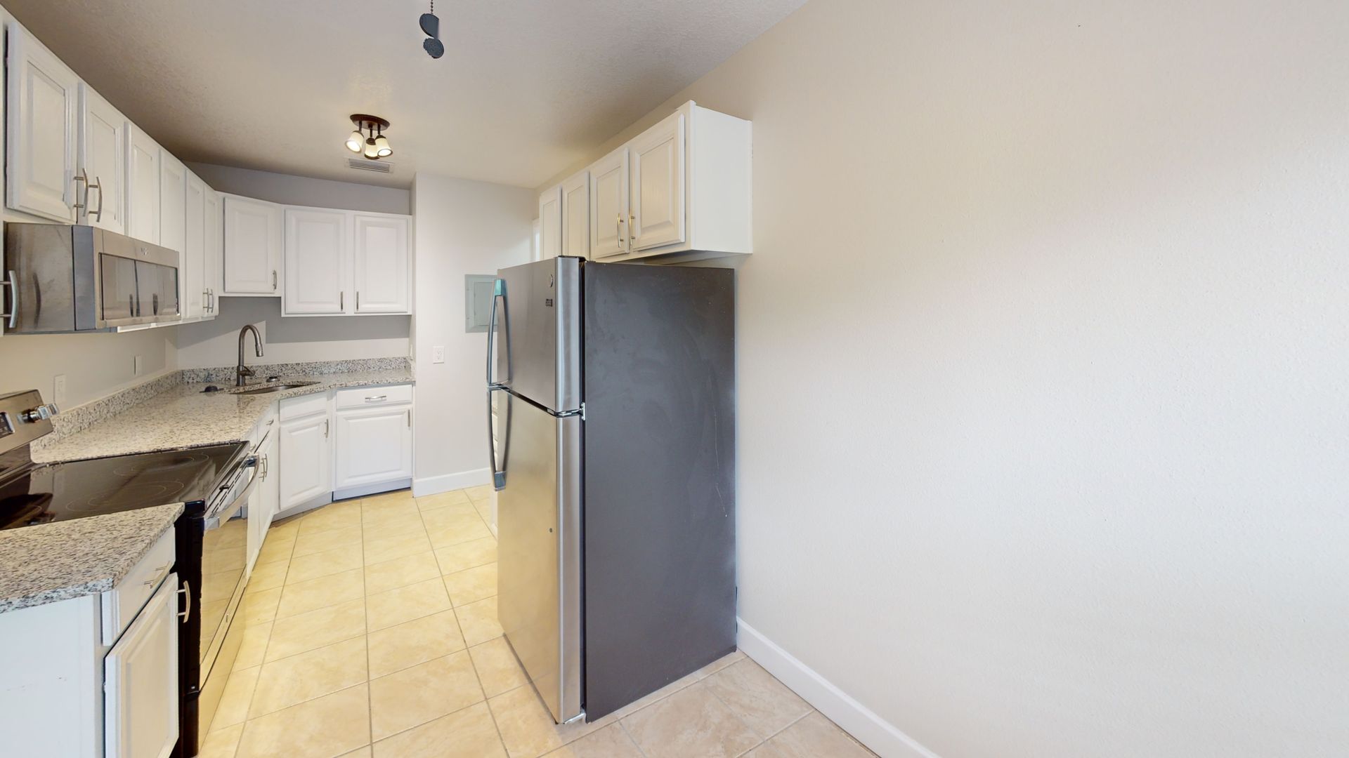 A kitchen with white cabinets , stainless steel appliances and a refrigerator.