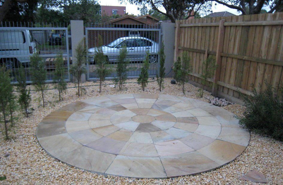 A Circular Stone Patio In Front Of A Wooden Fence — Leemark Design Services In Parramatta Park, QLD