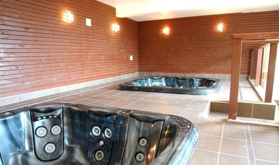 There Are Two Hot Tubs in a Room With a Brick Wall — Leemark Design Services In Parramatta Park, QLD