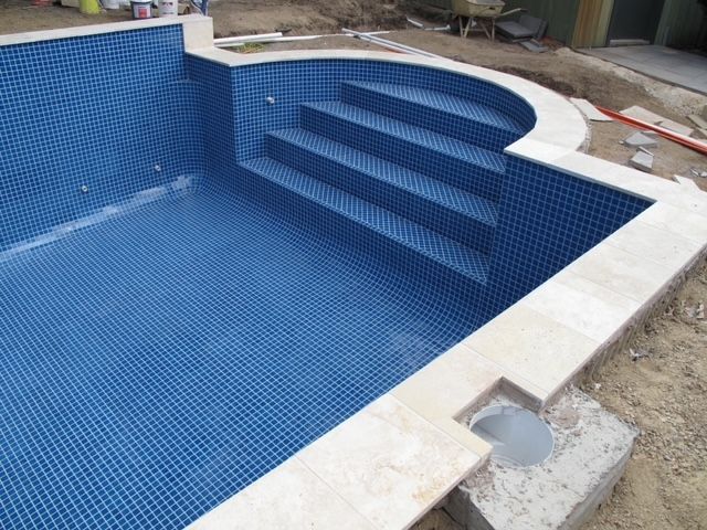 A Swimming Pool With Blue Tiles and Stairs is Being Built — Leemark Design Services In Parramatta Park, QLD