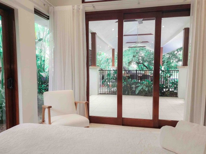 A Bedroom With a Bed, Chair and Sliding Glass Doors — Leemark Design Services In Parramatta Park, QLD