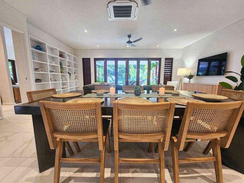 A Dining Room Table With Wicker Chairs in a Living Room — Leemark Design Services In Parramatta Park, QLD