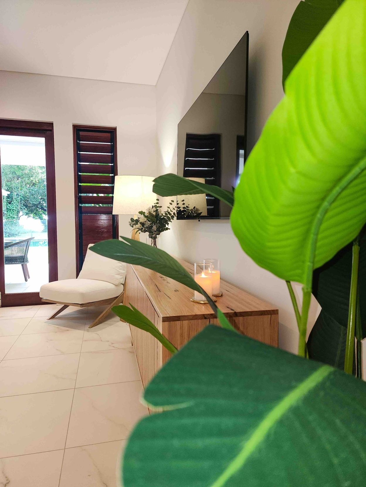 A Living Room With a Couch, Chair, Lamp and a Large Mirror — Leemark Design Services In Parramatta Park, QLD