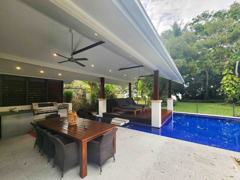 A Patio With a Table and Chairs Next to a Swimming Pool — Leemark Design Services In Parramatta Park, QLD