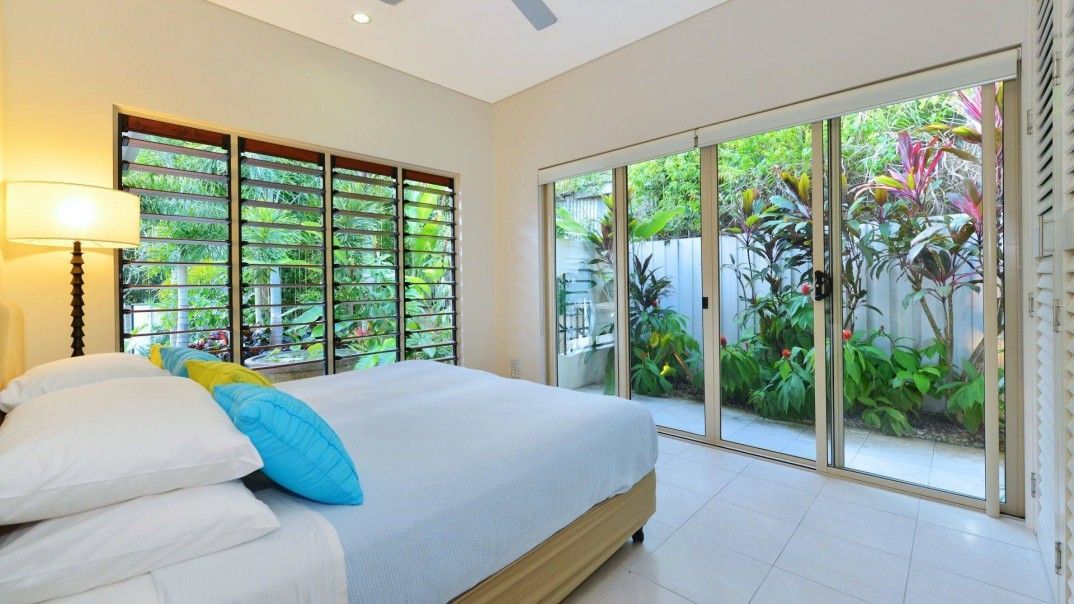 A Bedroom With a Large Bed and Sliding Glass Doors Leading to a Garden — Leemark Design Services In Parramatta Park, QLD