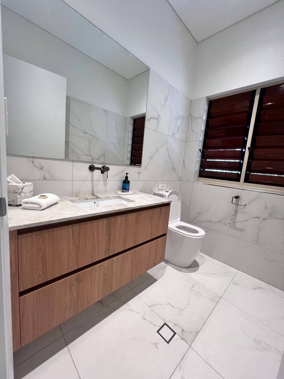 A Bathroom With a Sink, Toilet, Mirror and Window — Leemark Design Services In Parramatta Park, QLD
