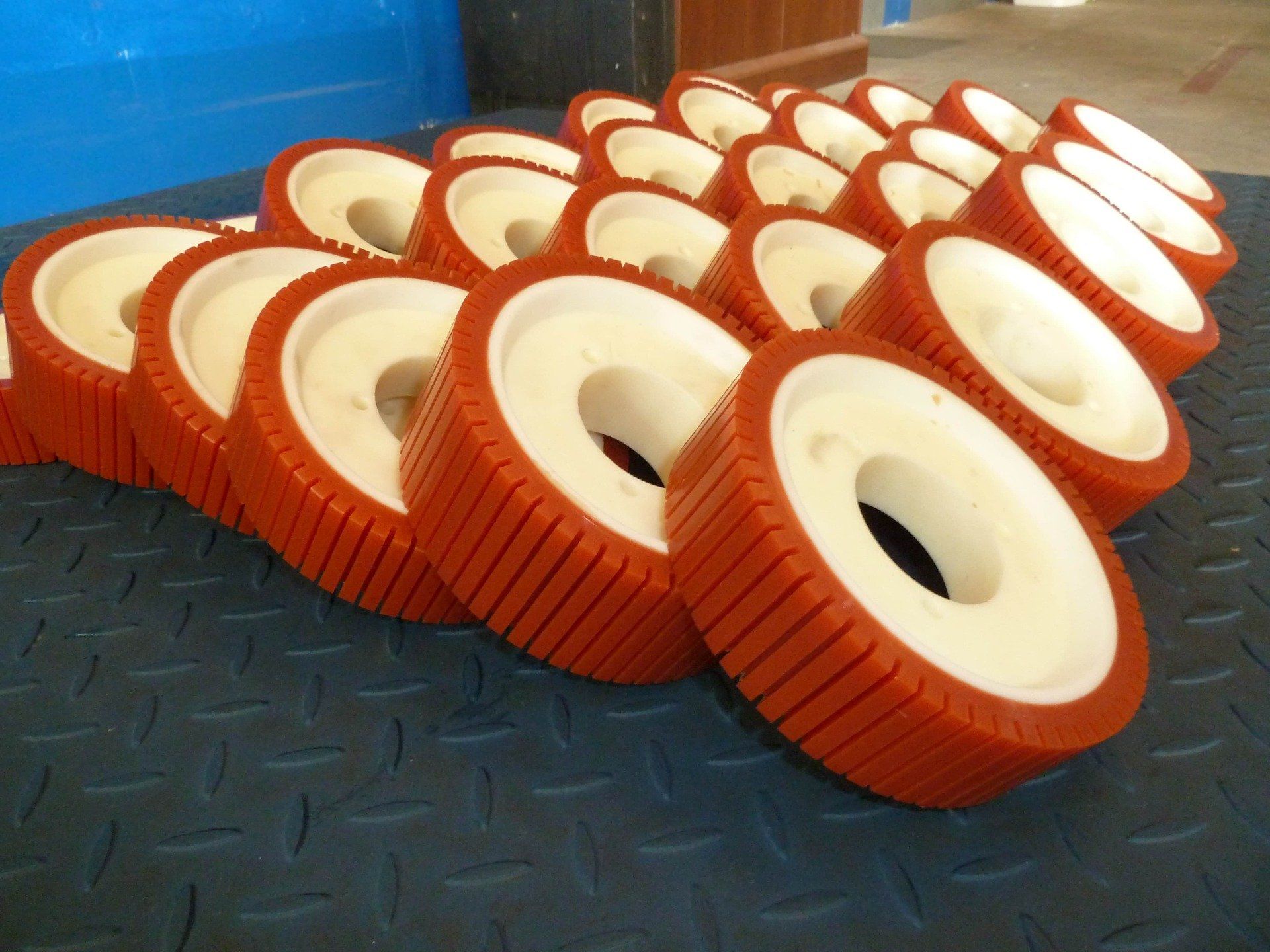Un mucchio di ruote industriali arancioni e bianche su una superficie blu testurizzata.