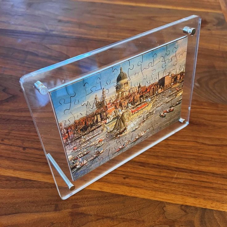 Una imagen de una ciudad en un marco transparente sobre una mesa de madera.