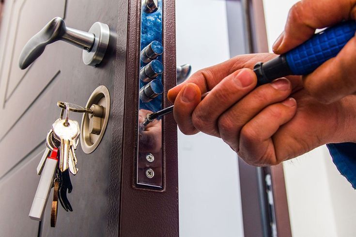 Una persona está arreglando una cerradura de puerta con un destornillador.