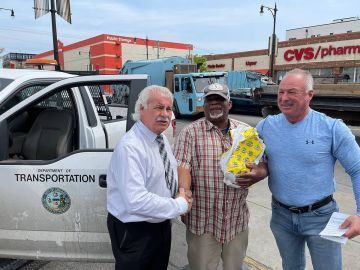Three men shaking hands near a Department of Transportation truck