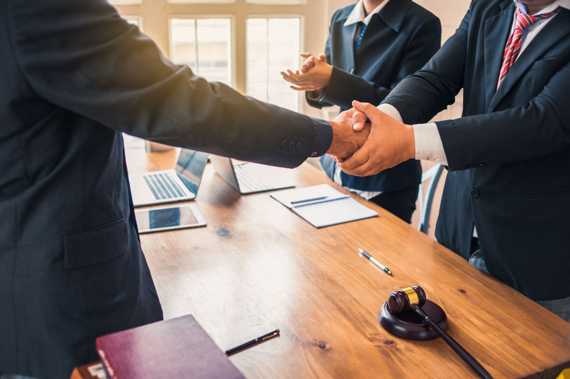 A group of men are shaking hands over a wooden table.