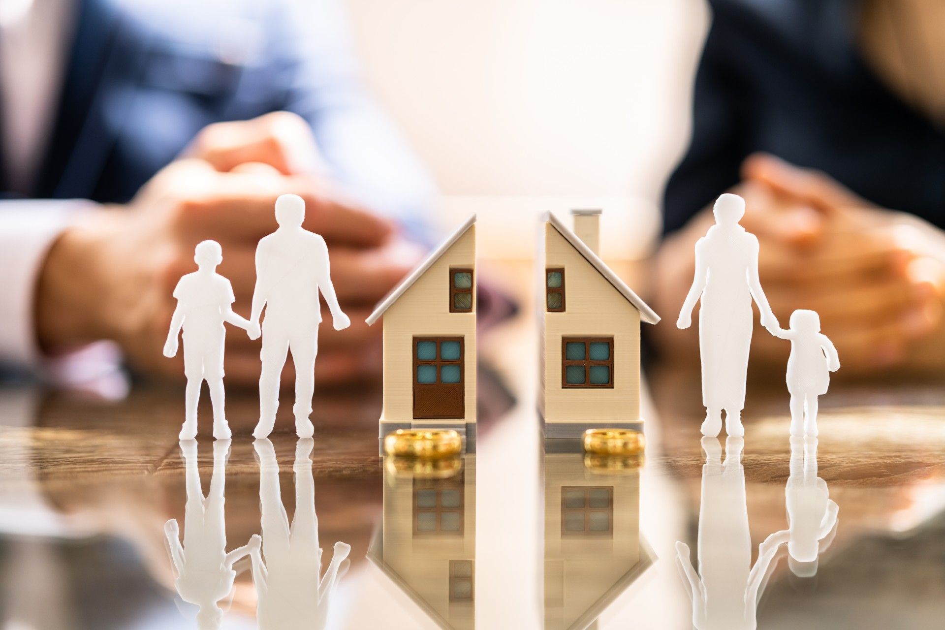 A family is sitting at a table with a model house and a model family.