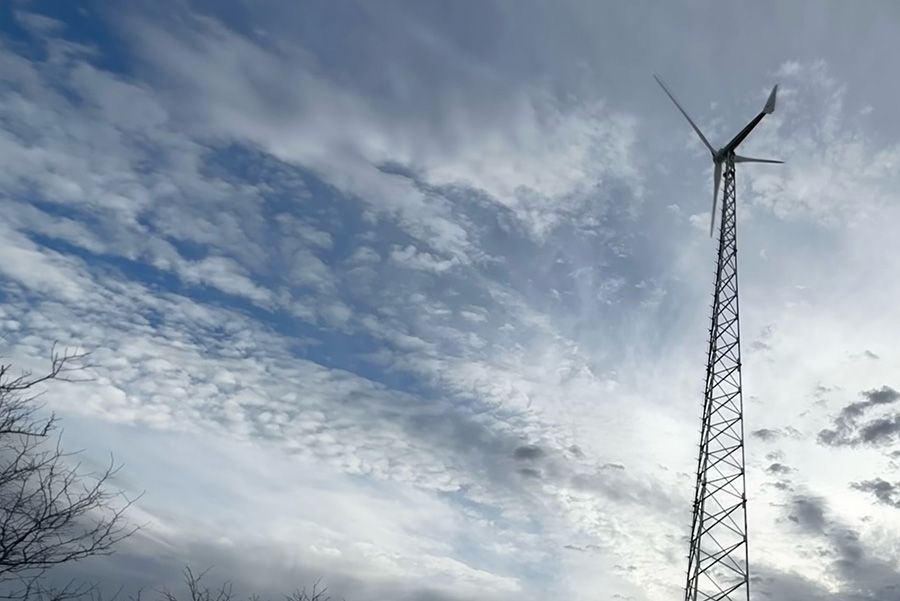 A wind turbine is sitting on top of a tower against a cloudy sky.