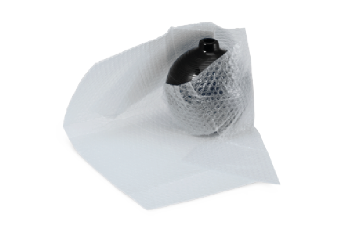 Eine Flasche ist in Luftpolsterfolie eingewickelt und auf einem Stück Papier platziert.