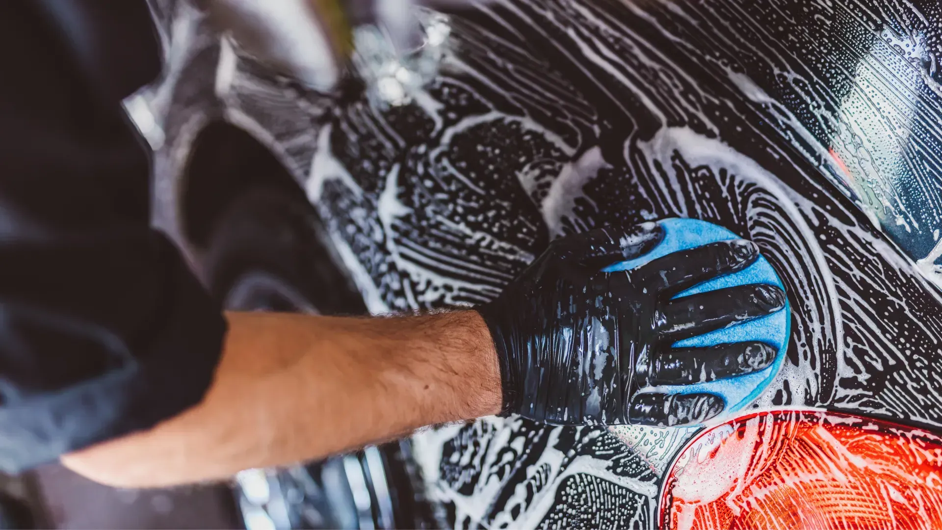 A man is washing a car with soap and water.
