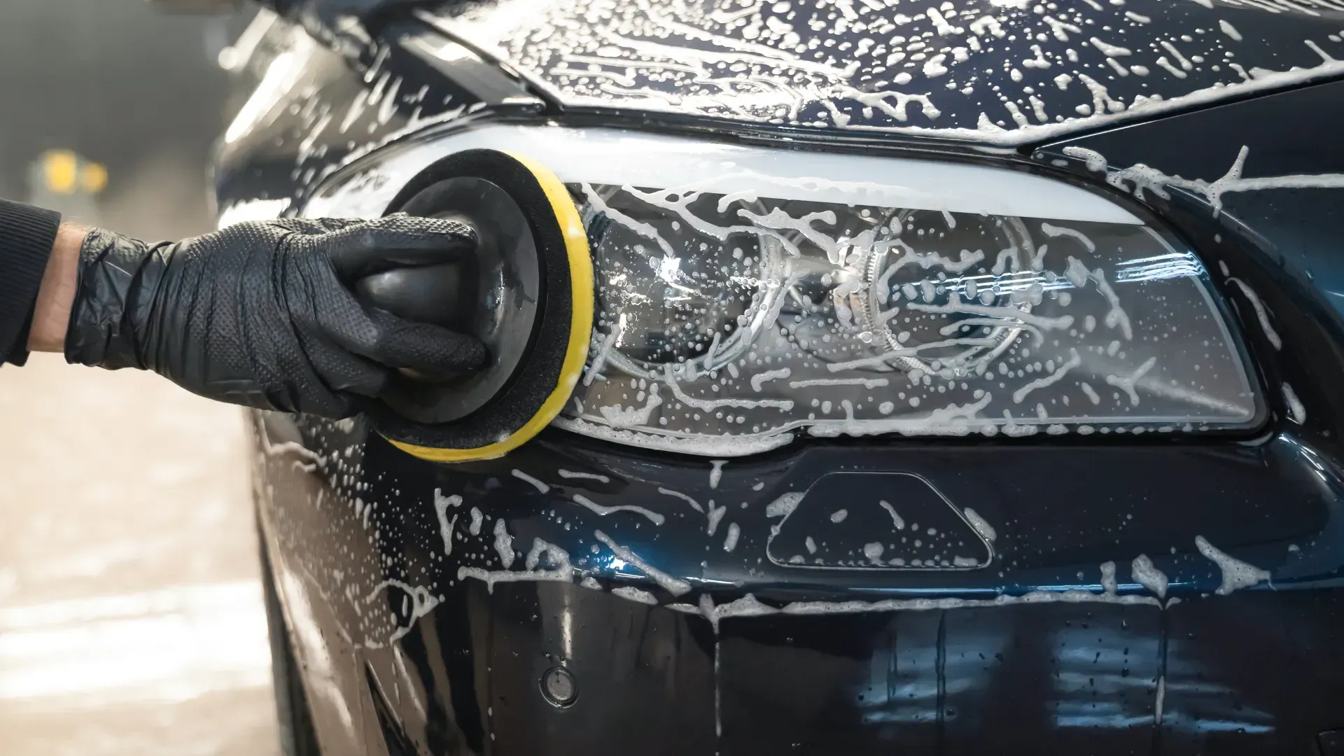 A person is polishing the headlight of a car.