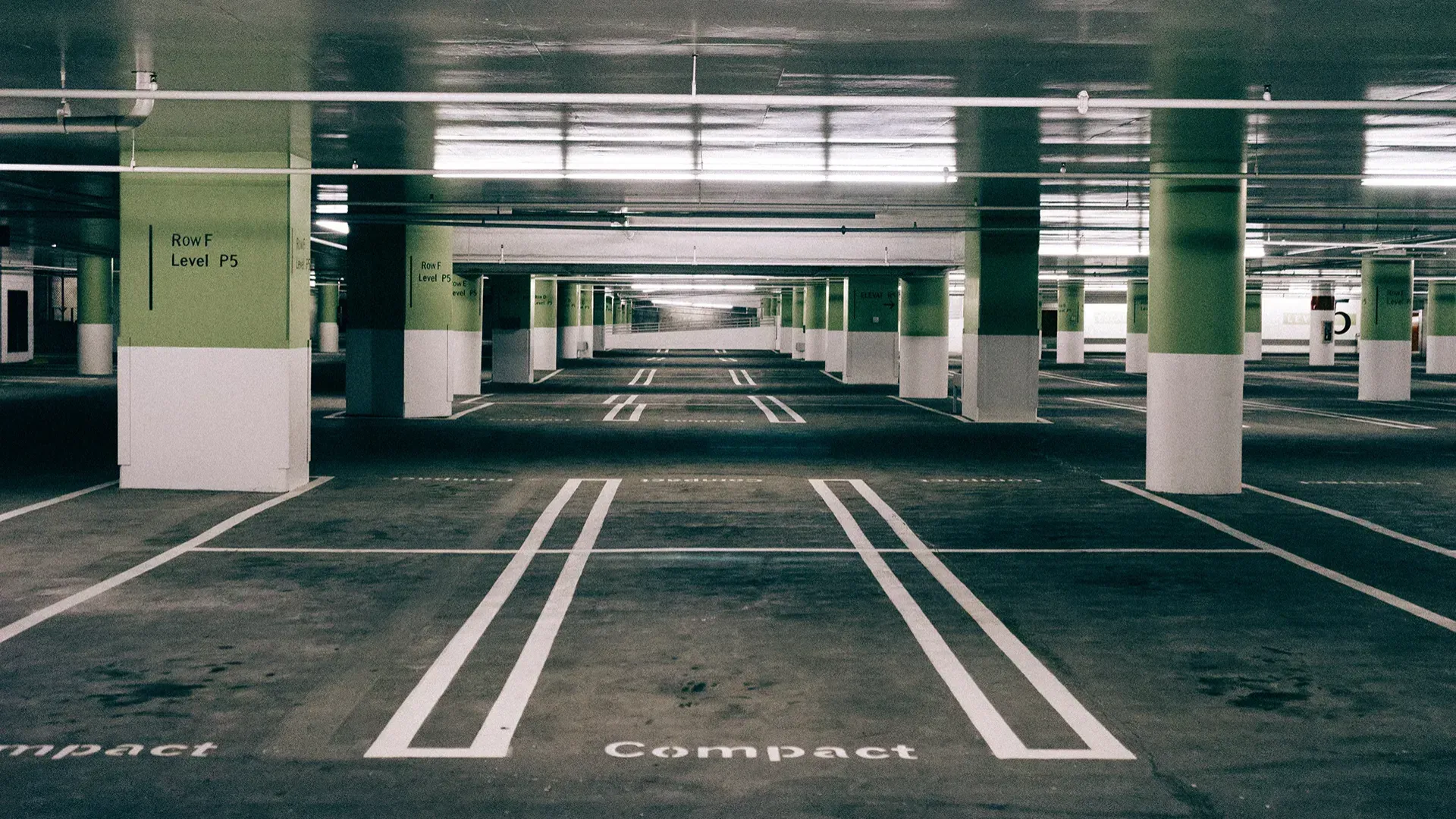 An empty parking garage with green and white pillars