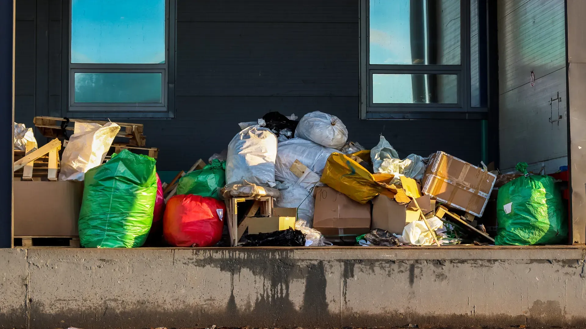A pile of trash is sitting on the sidewalk in front of a building.
