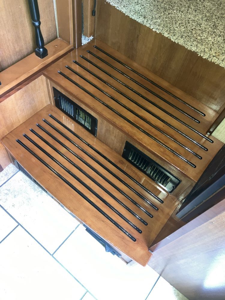 Wooden RV steps with black accents and air vents, leading to a countertop.