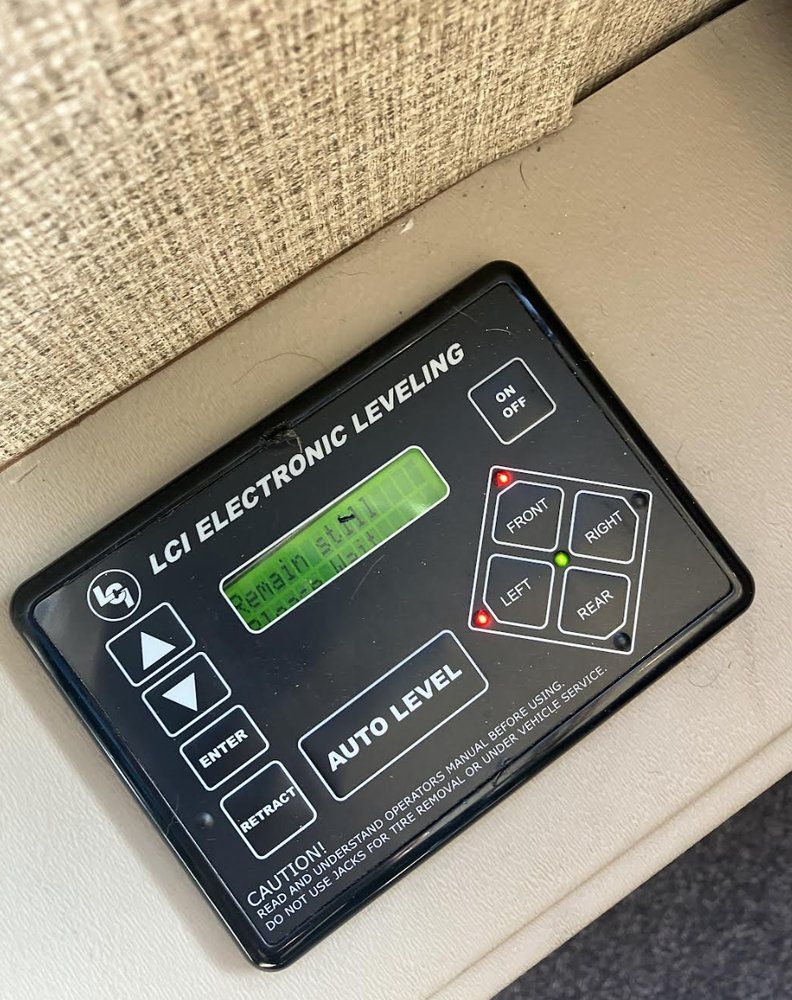LCI electronic leveling control panel in an RV. The panel is black with a green display and buttons for leveling the vehicle.