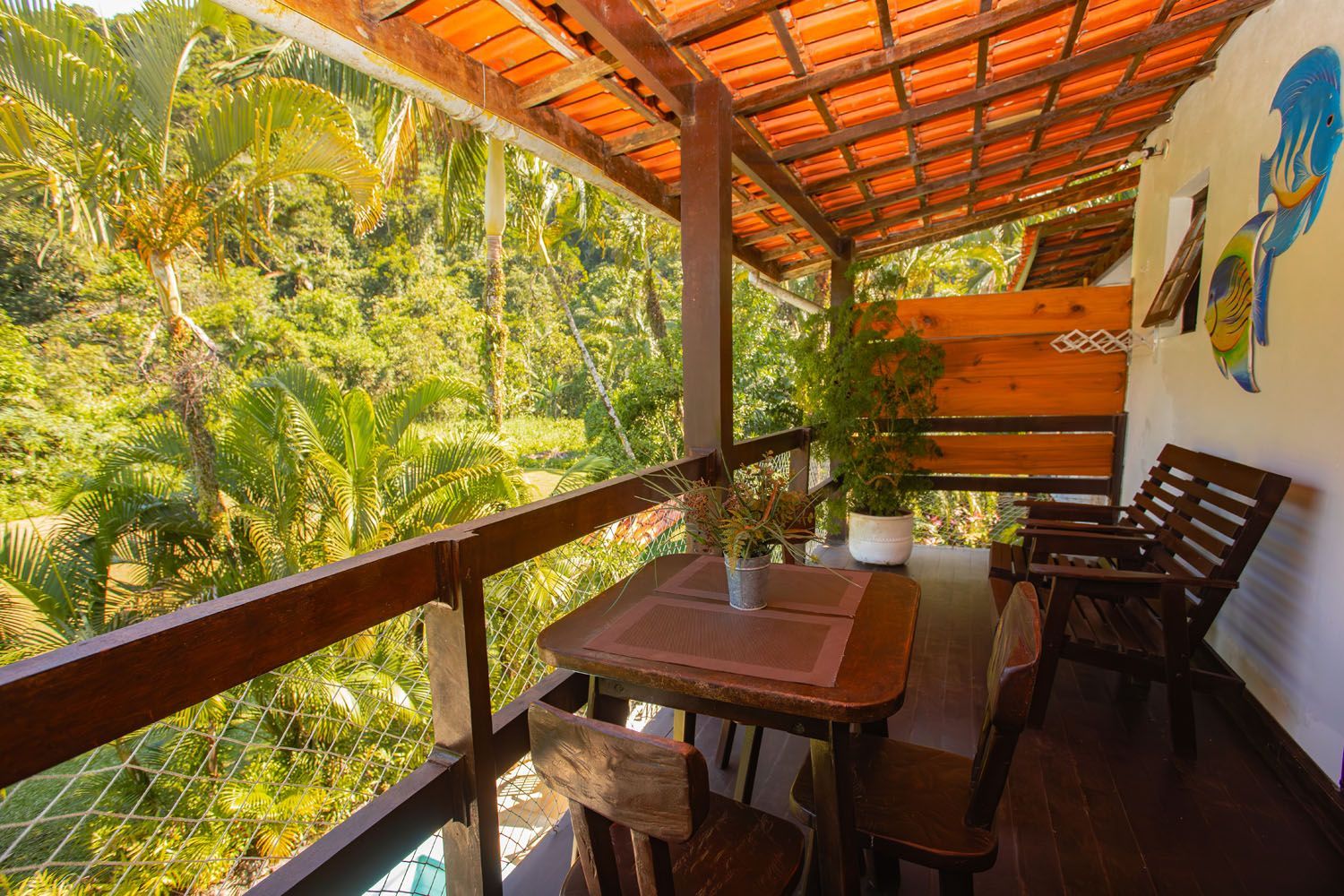 Uma varanda com mesa e cadeiras com vista para uma floresta verdejante.