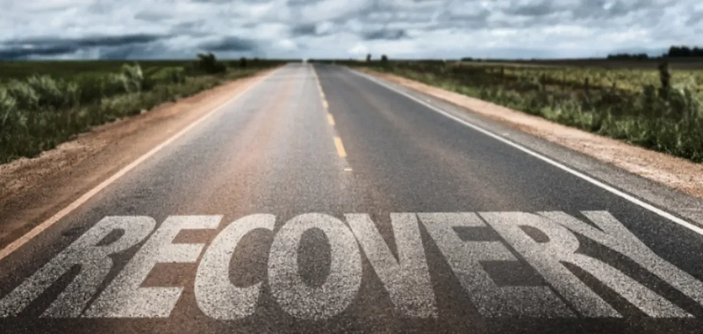 The word recovery is painted on the side of a road.