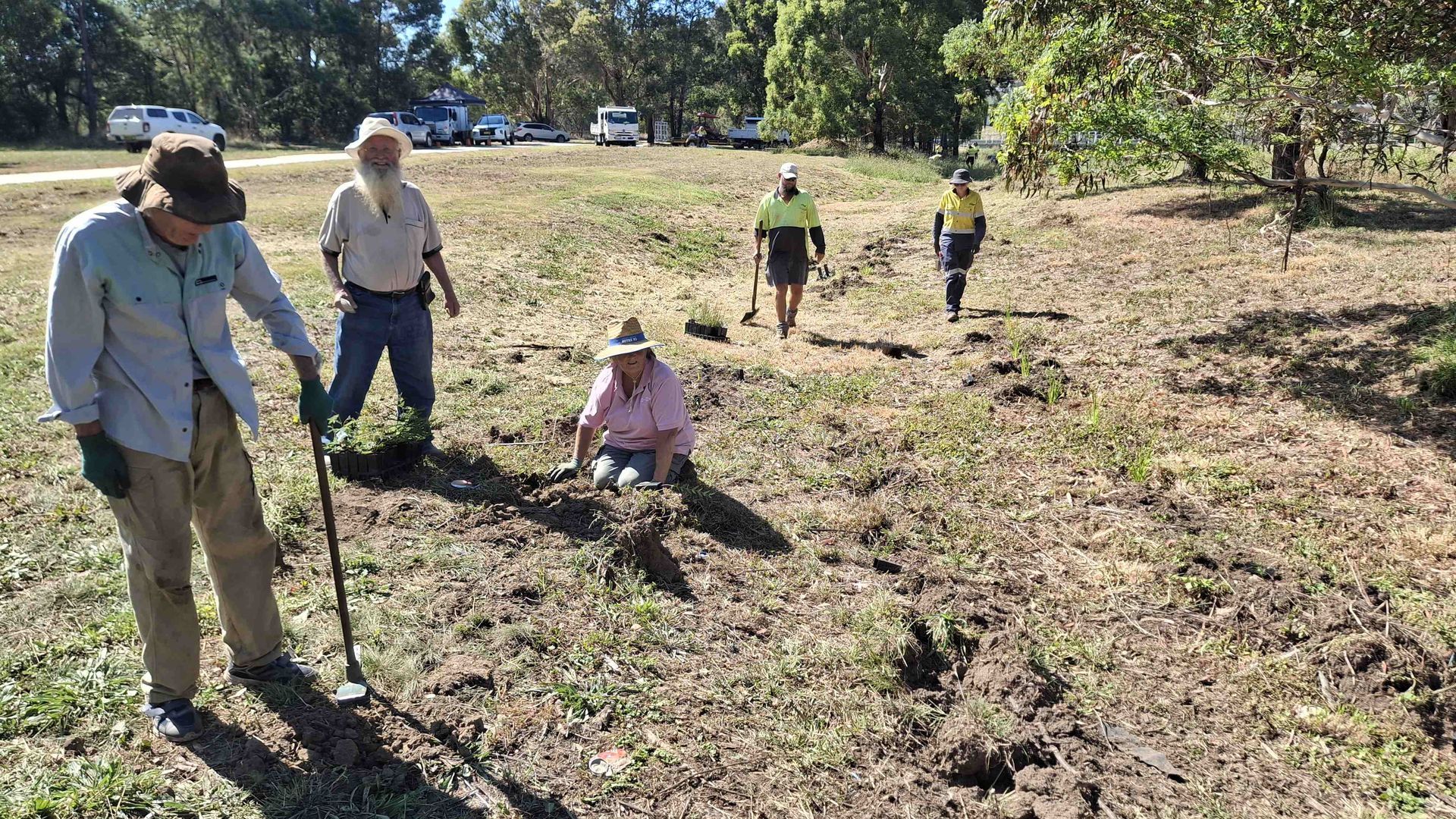 A group of people preparing a field for planting of new trees and shrubs.