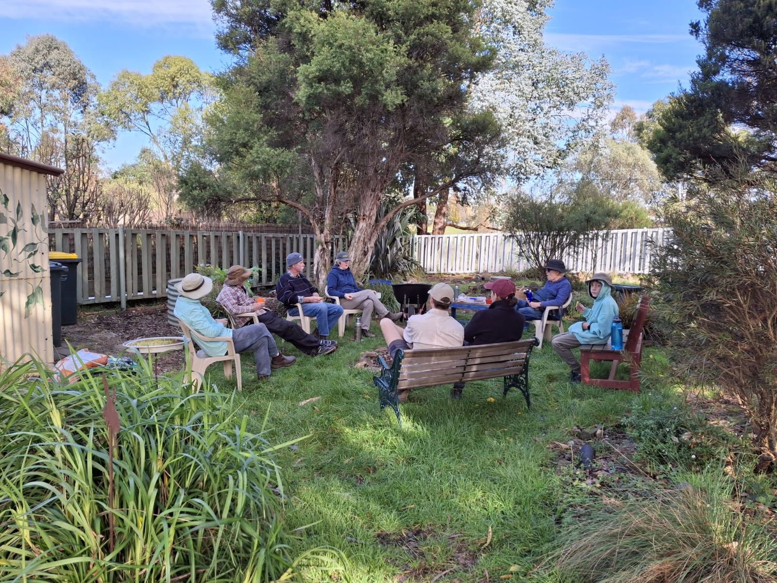 A group of people are sitting in a circle in the grass.