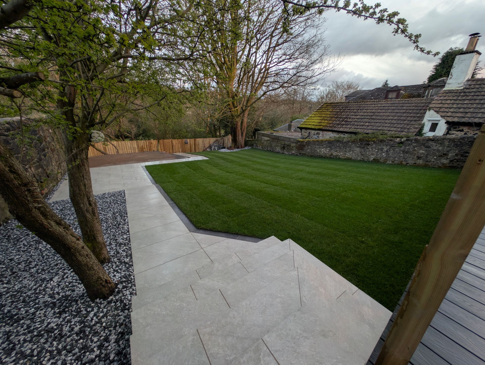 Finished hard landscaping project with porcelain patio, lawn, and drainage system in Central Scotland