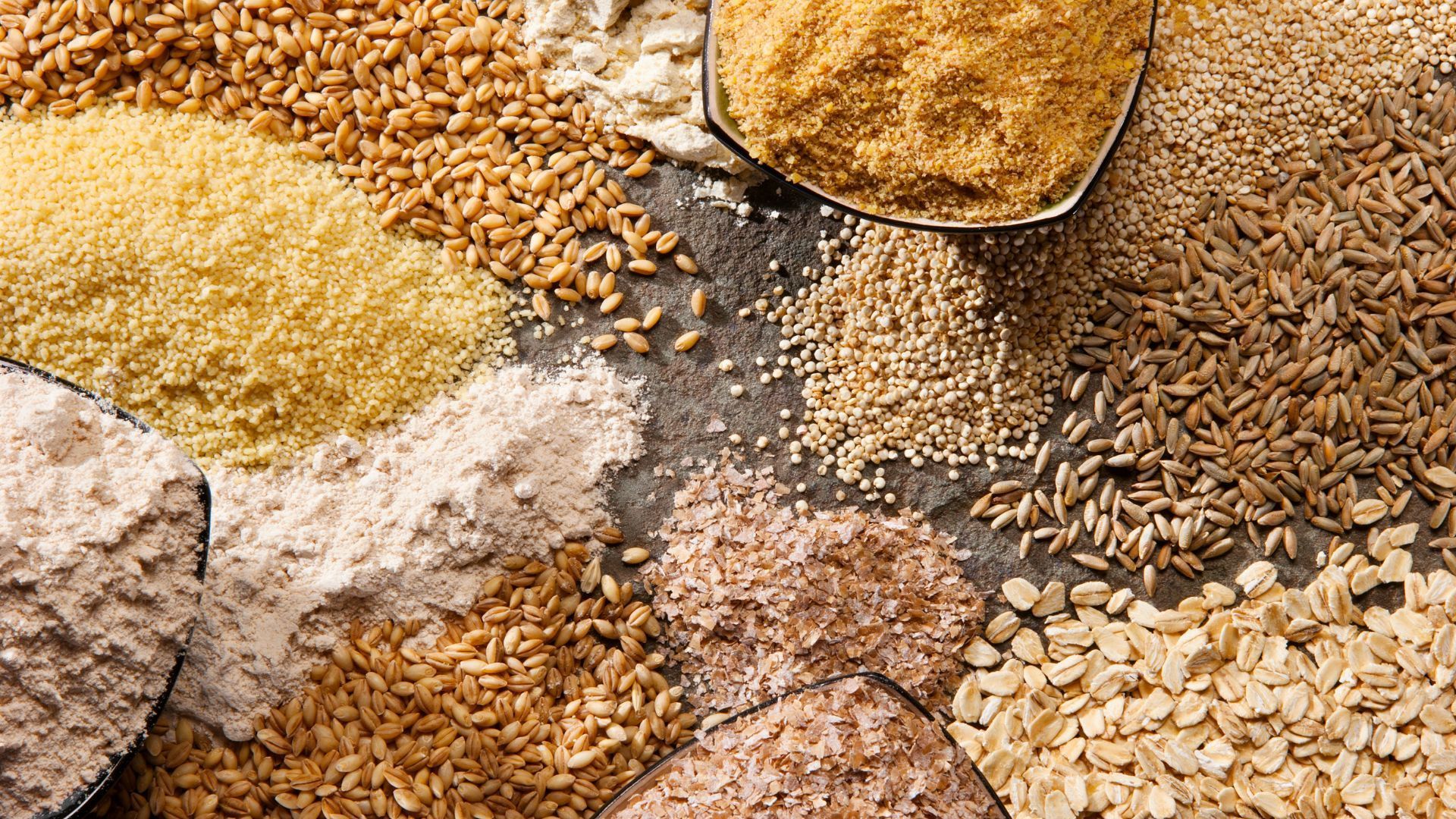 Various grains and seeds in a spoon, showcasing a mix of textures, colors, and shapes.