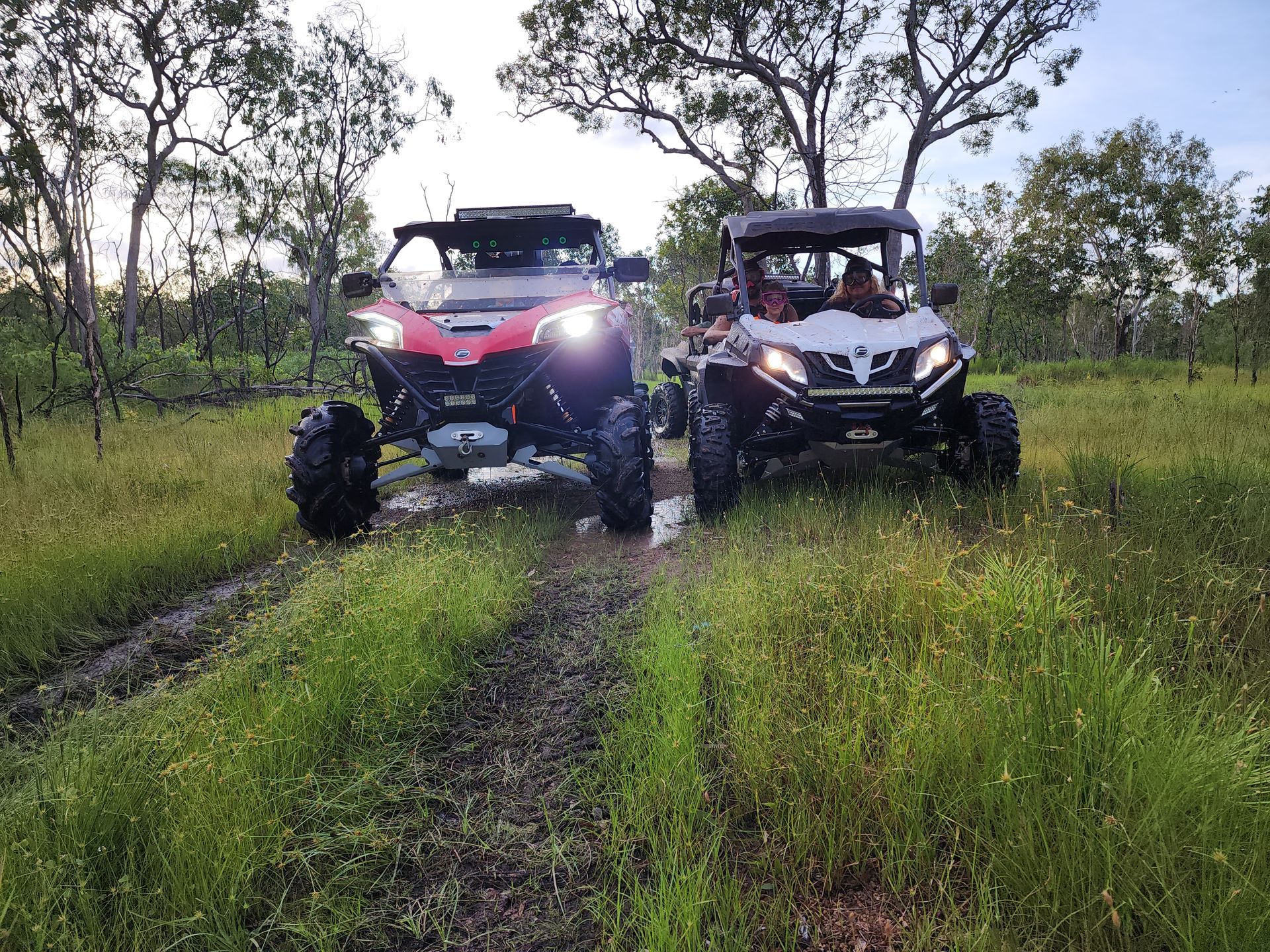 Two atvs are parked next to each other in a grassy field.