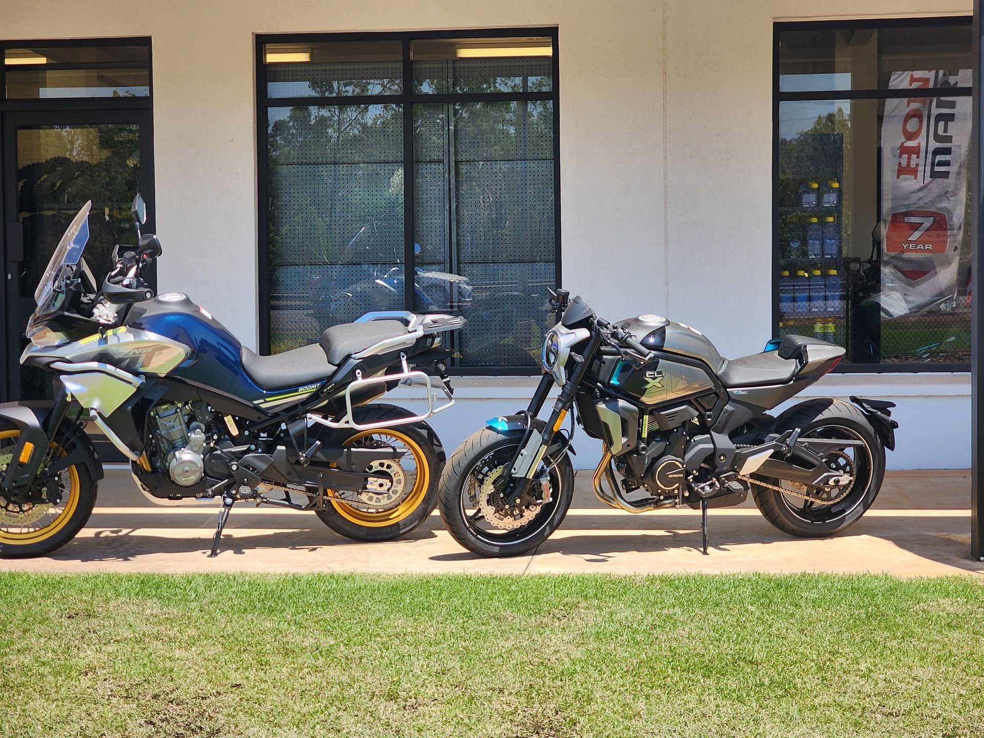 Two motorcycles are parked in front of a building.