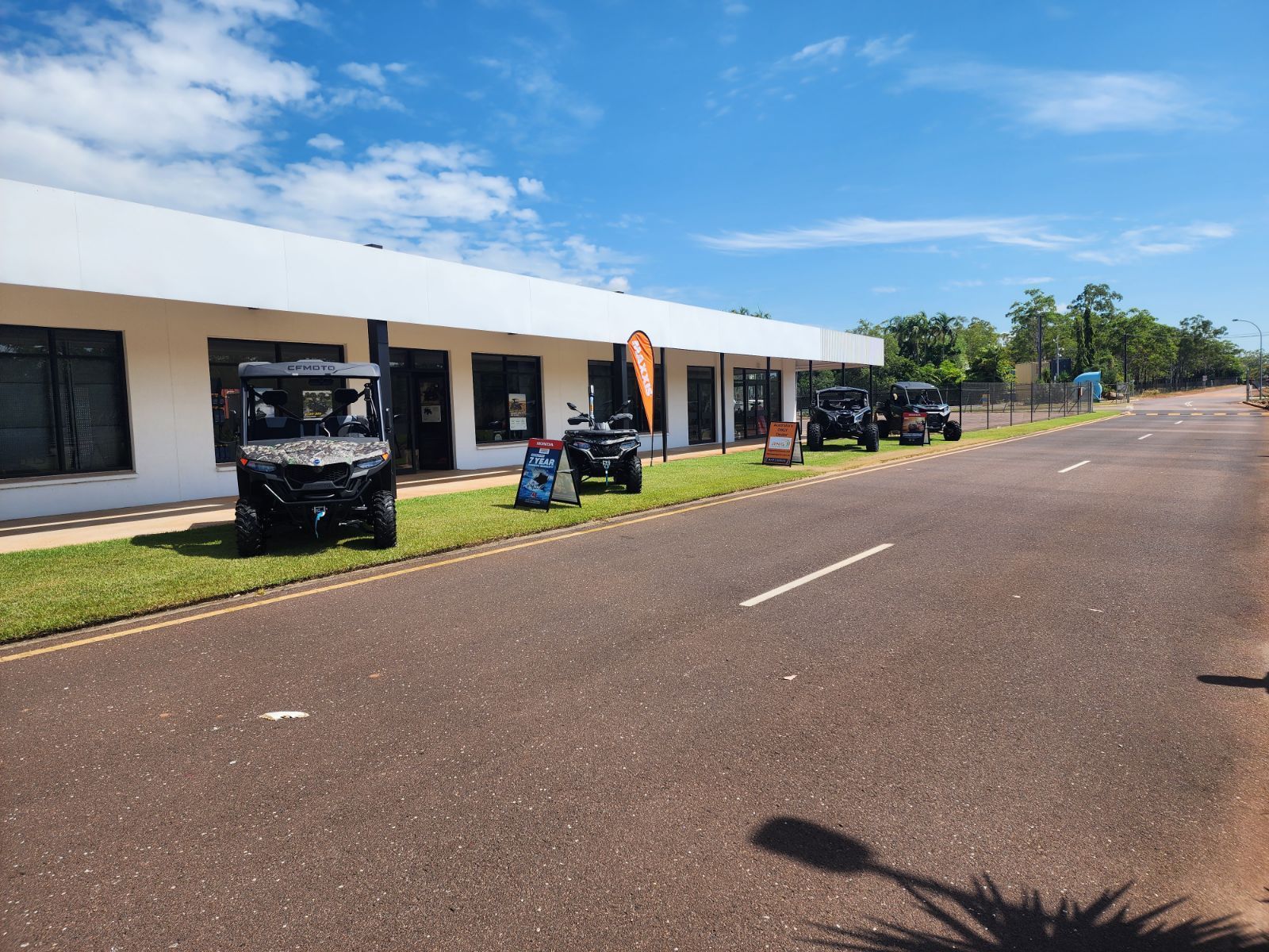 A row of atvs are parked on the side of the road in front of a building.