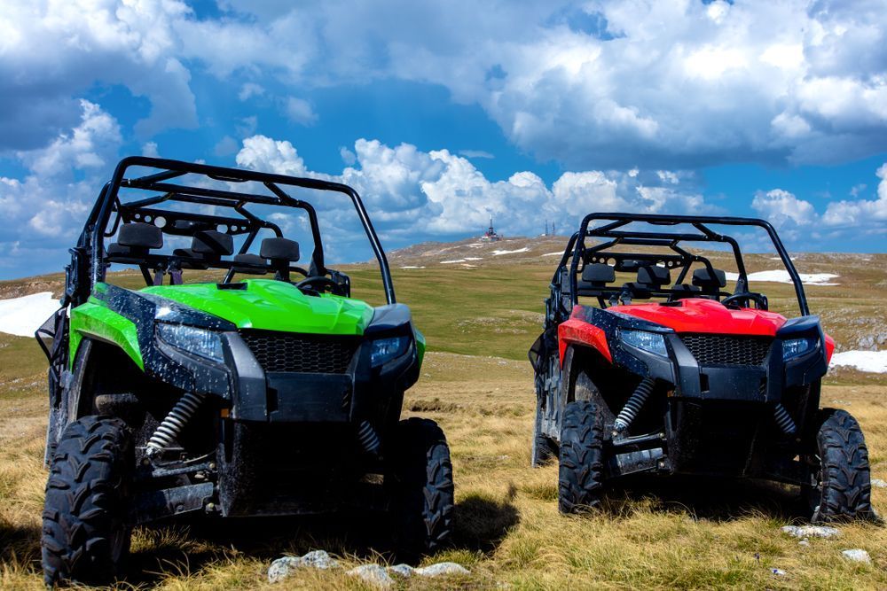 Two atvs are parked next to each other in a grassy field.