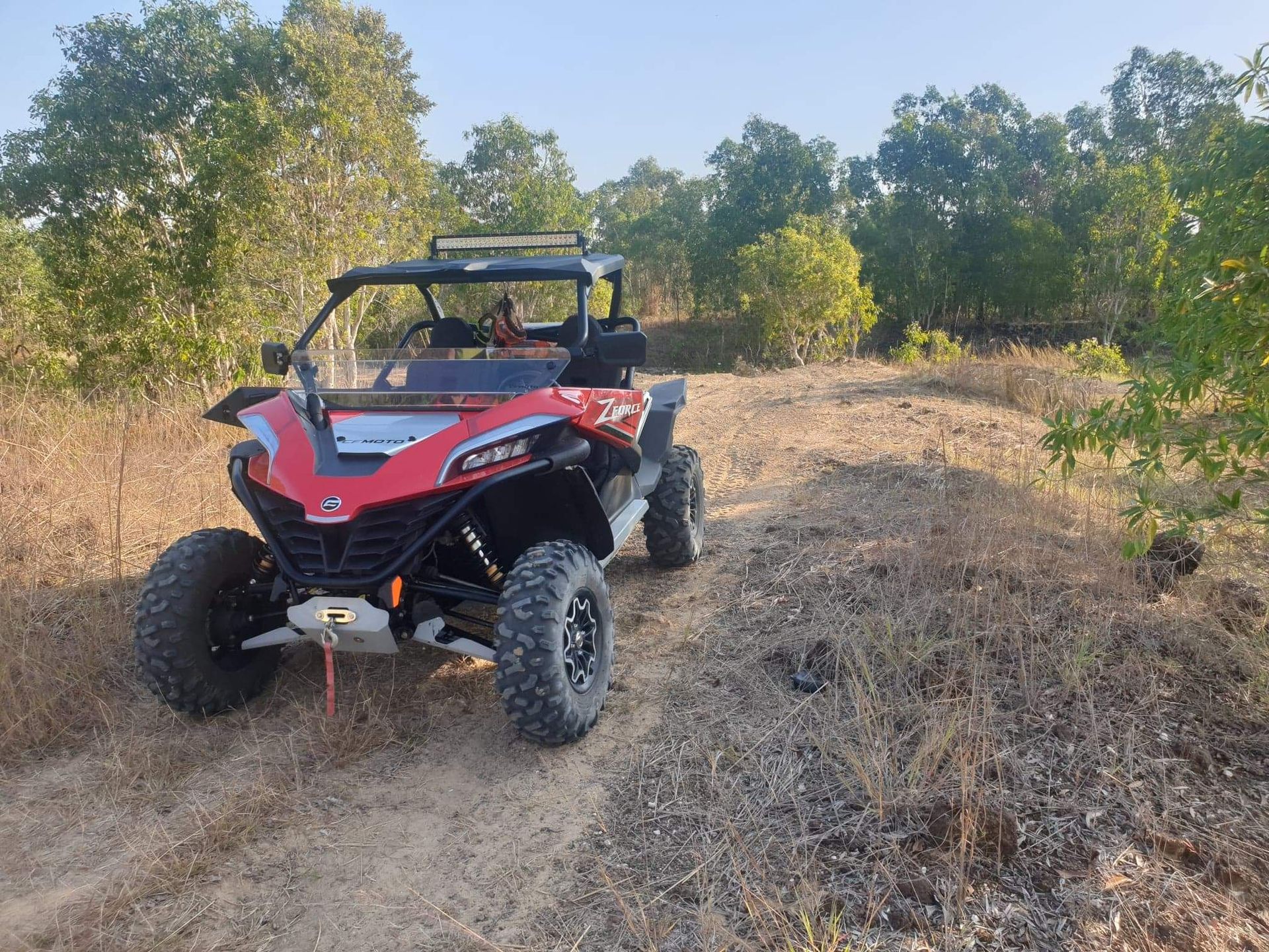 A red atv is parked on a dirt road in a field.