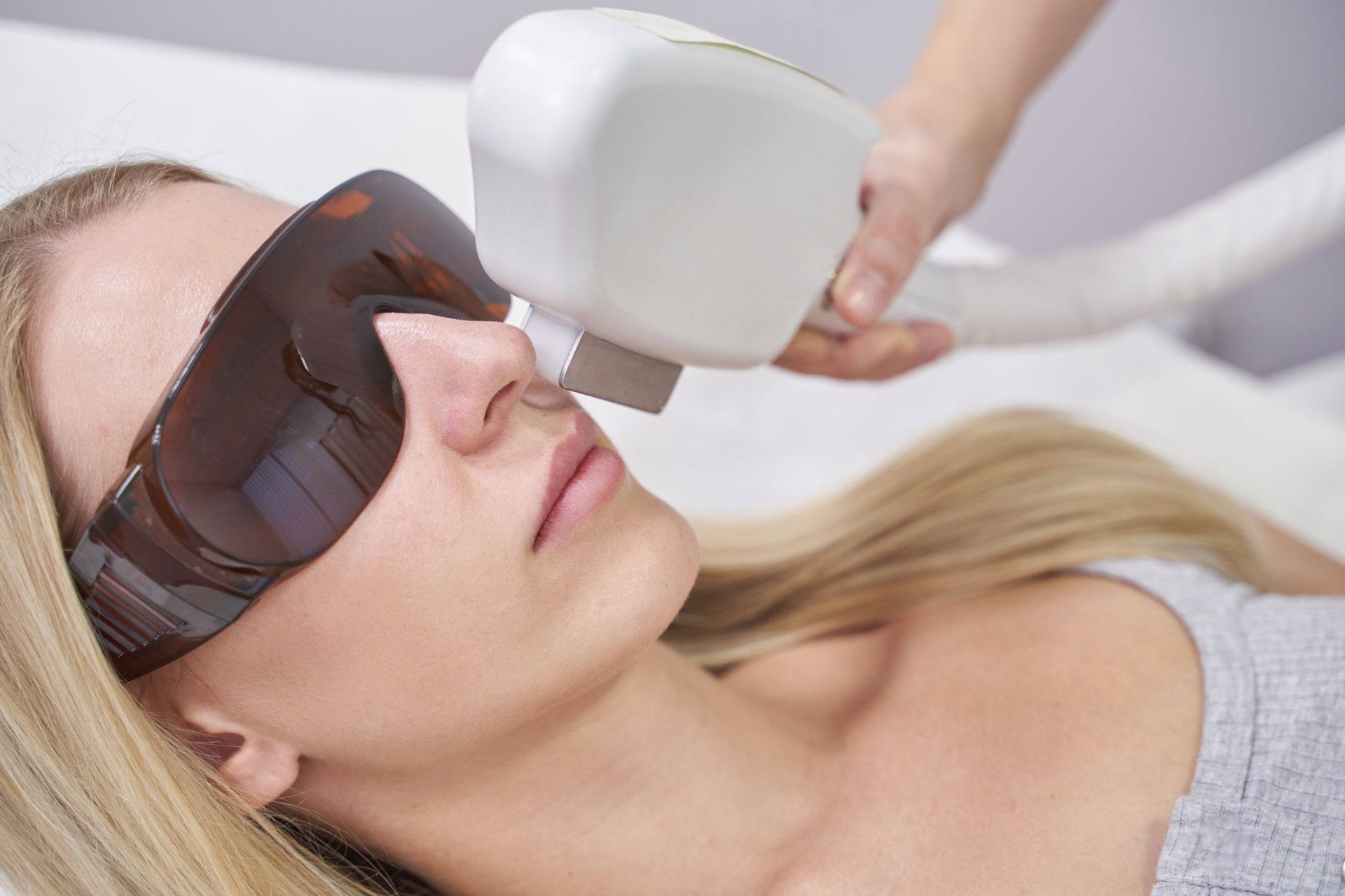 A woman is getting a laser hair removal treatment on her face.