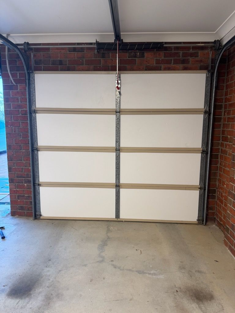 White garage door with horizontal panels, inside a brick garage.