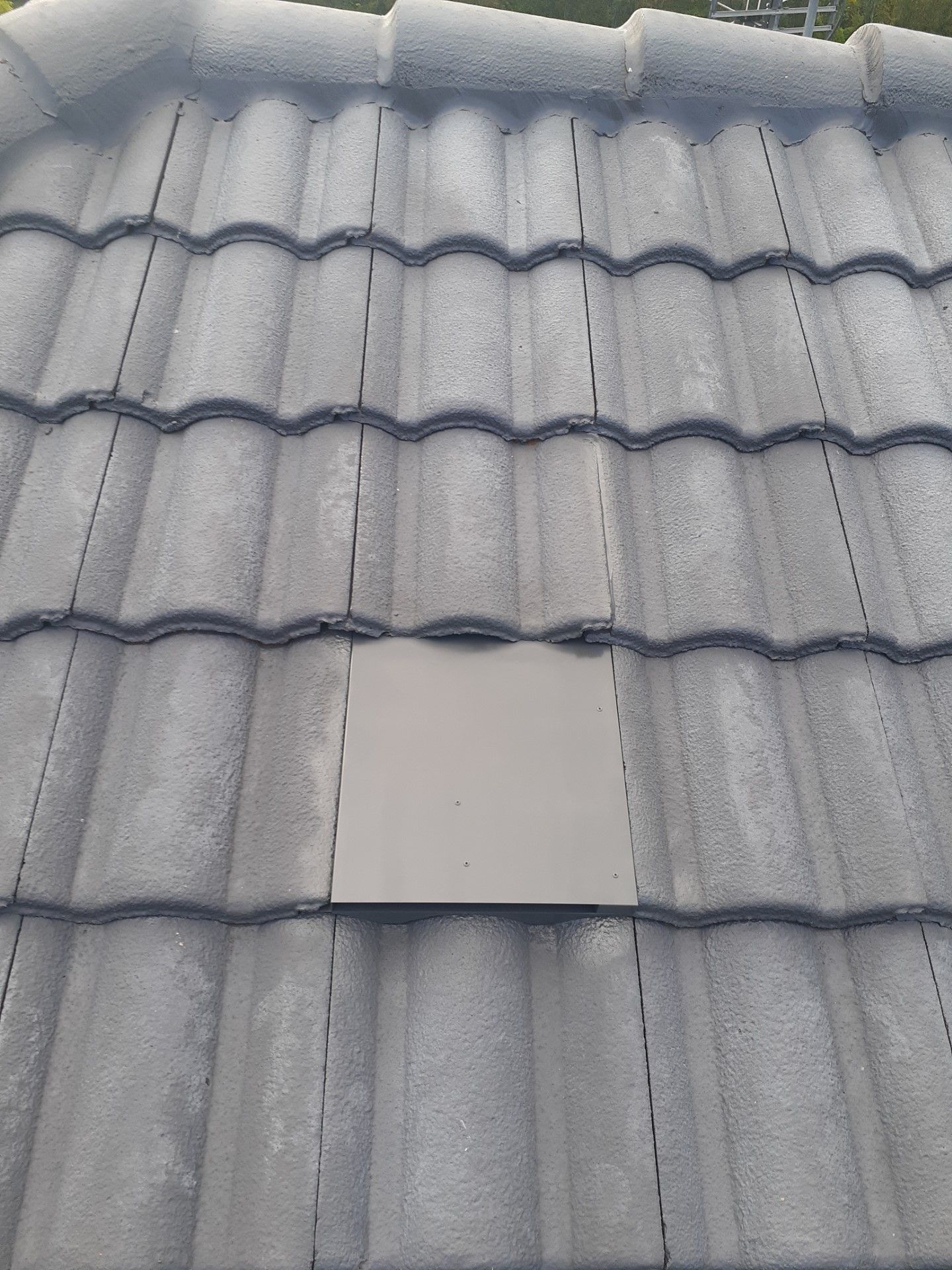Gray tiled roof with a light-colored square tile among the others.— Vent Wise in Twin Waters, QLD