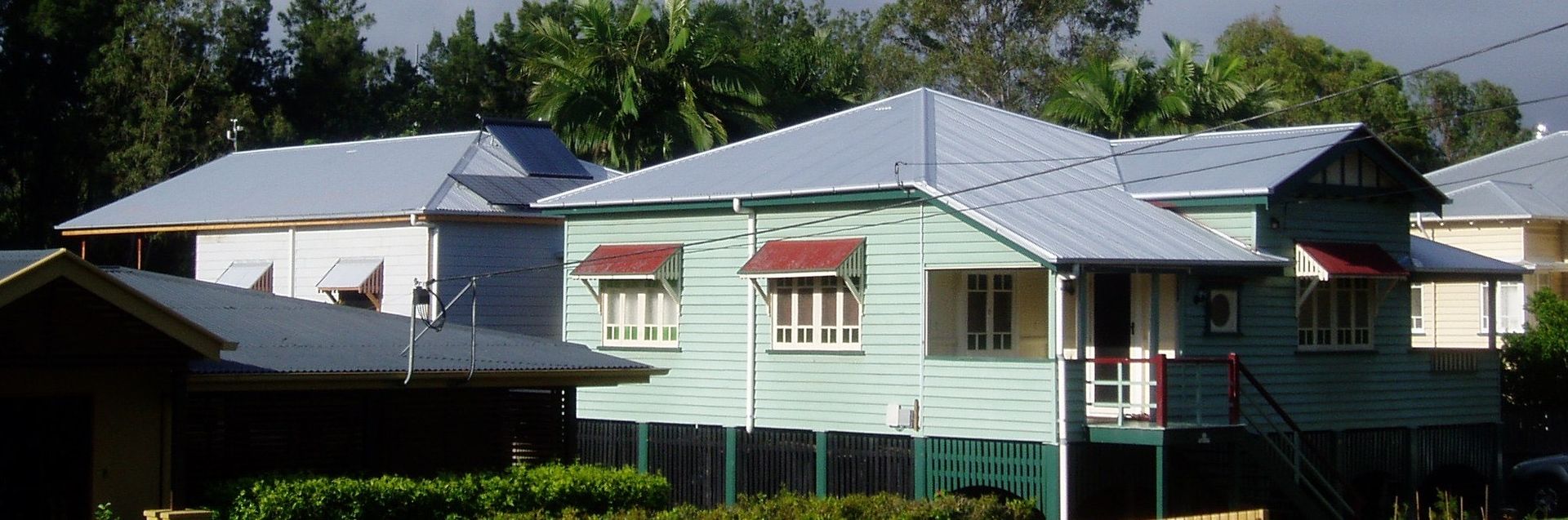 Houses with light blue exteriors, red awnings, and silver roofs, set amongst trees.— Vent Wise in Twin Waters, QLD