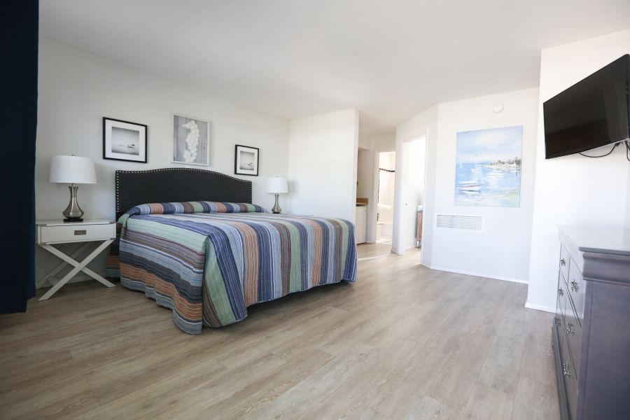 A bedroom with a large bed and a flat screen tv on the wall.