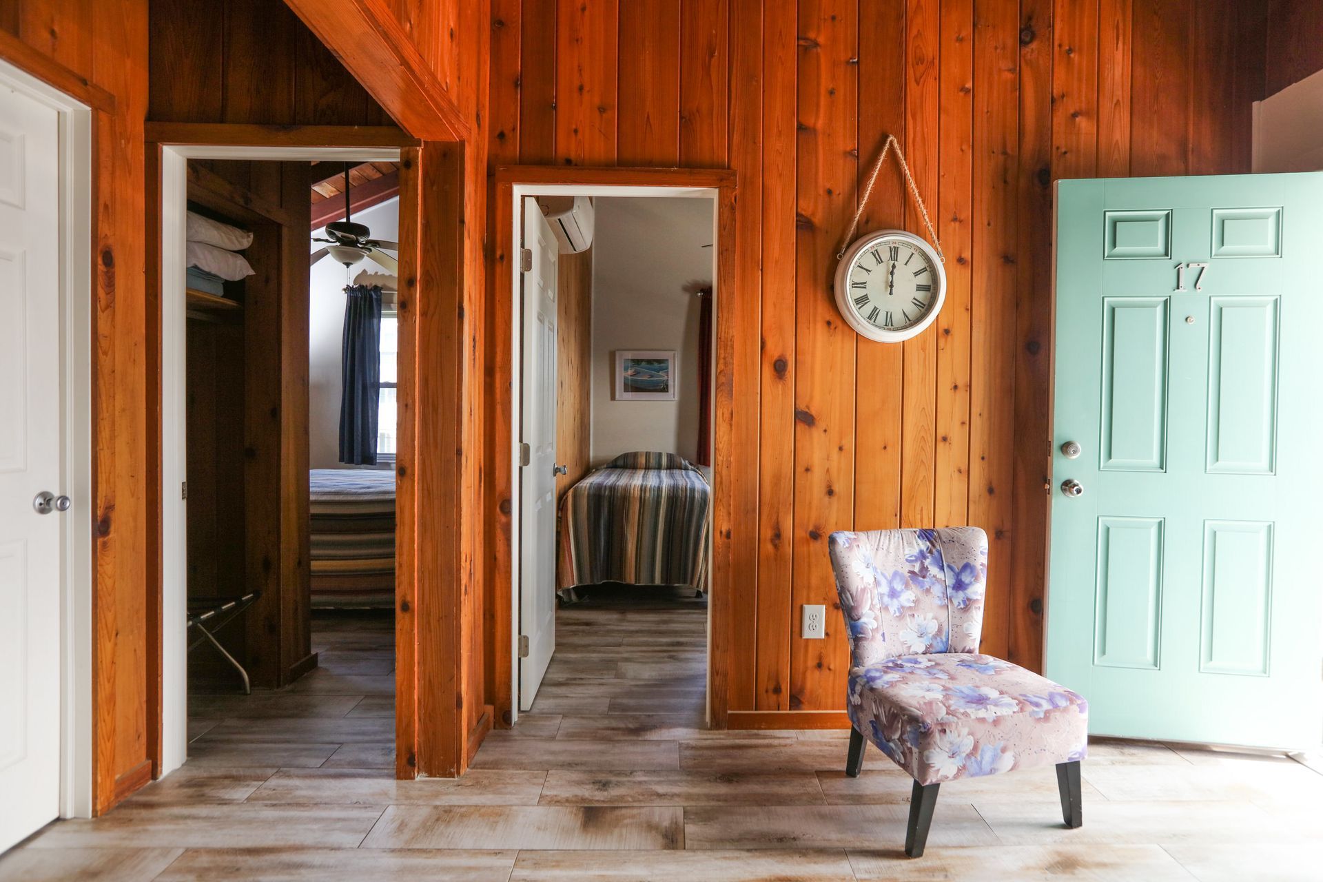 There is a chair in the middle of the room with a clock on the wall.