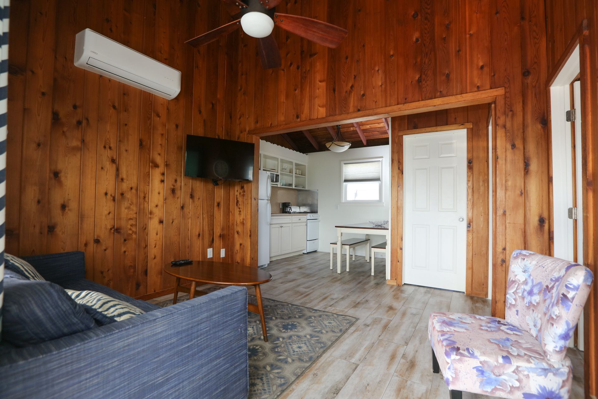A living room with a couch , chair , television and ceiling fan.