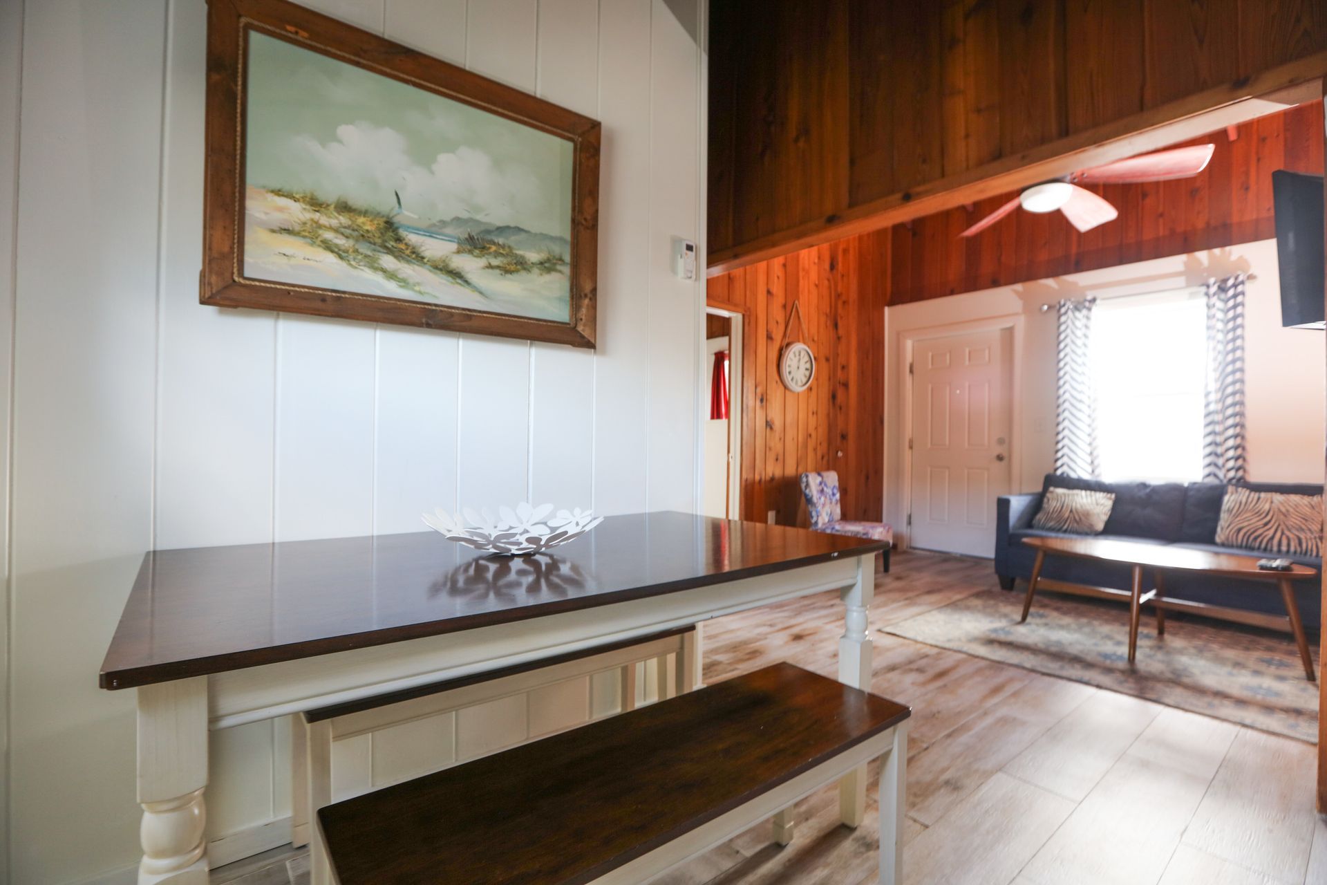 A living room with a table and bench and a painting on the wall.