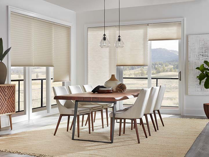 A dining room with a table and chairs and sliding glass doors.